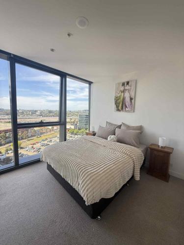 a bedroom with a large bed and a large window at Cozy and Comfortable 2BR Apartment with master Ensuite and bathrooms in Melbourne