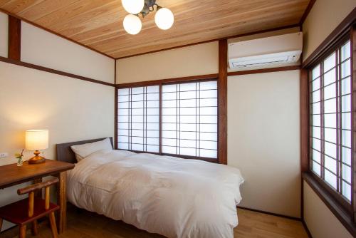 a bedroom with a white bed and two windows at 女性専用お宿にこに in Izumo