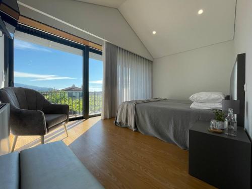 a bedroom with a bed and a chair and a window at Casa das Branquinhas - Férias no Minho com piscina! in Ponte de Lima