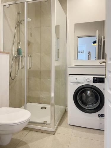 a bathroom with a washing machine and a washer at Le jardin de L'Hippodrome in Chantilly