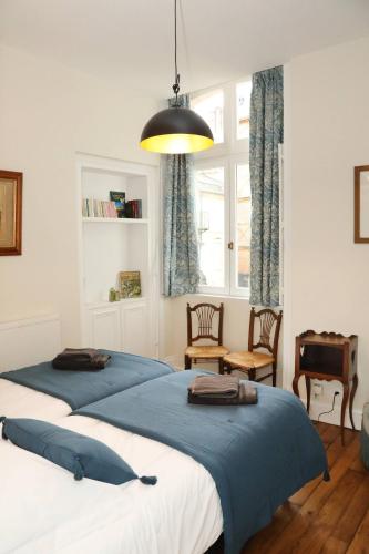 a bedroom with two beds and a pendant light at Le jardin de L'Hippodrome in Chantilly
