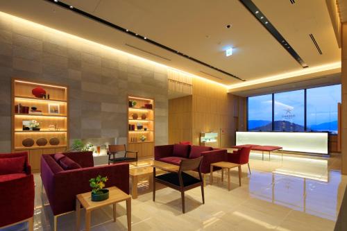 a living room with red furniture and a large window at Candeo Hotels Nara Kashihara in Kashihara