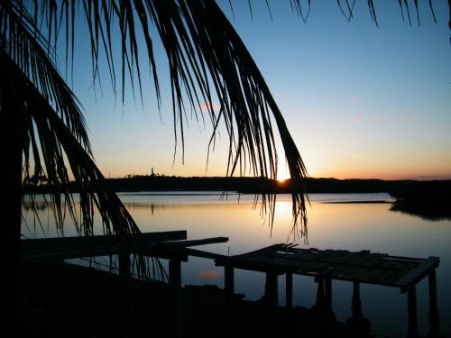 a sunset over a body of water with a dock at Igarakuê Flat in Japaratinga