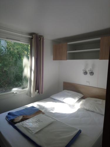 a bed in a bedroom with a window and a bedvisor at Camping Les Pins de Sel in Saint-Augustin