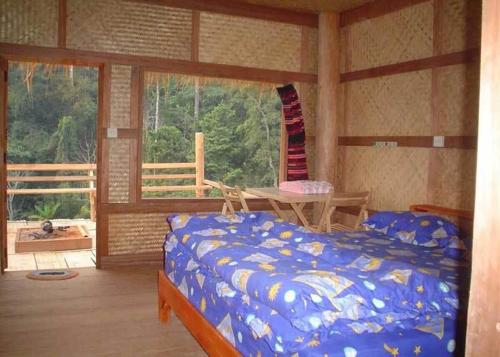 a bedroom with a bed and a table and a window at Akha Hill House in Ban Doi Hang