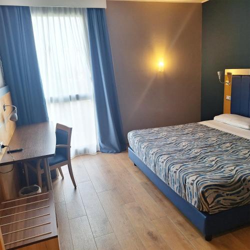a hotel room with a bed and a desk and a window at Idea Hotel Milano San Siro in Milan