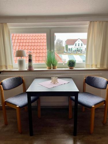 a table and two chairs in front of a window at Dat Kapitänshuus in Carolinensiel