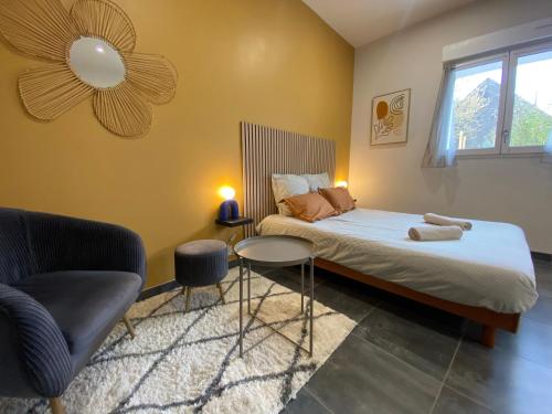 a bedroom with a bed and a chair and a window at Le Petit Francillon in Villebarou