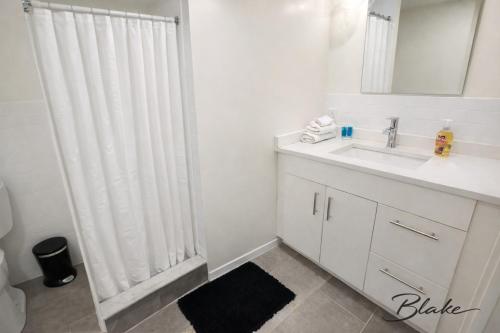 a white bathroom with a shower curtain and a sink at Trumbull Apartments Elevator WI-FI XL CENTER Hartford CT in Hartford