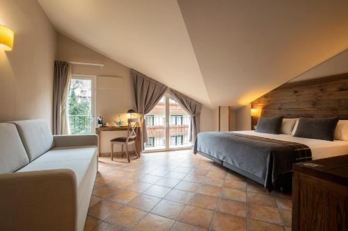 sypialnia z łóżkiem, kanapą i oknem w obiekcie Hotel Màgic Ski by Nexta w mieście La Massana