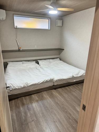 a small bed in a small room with a window at VILLA TSUKUNAMI aoshima in Miyazaki