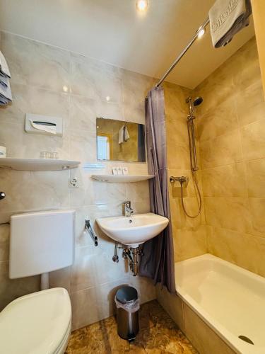 a bathroom with a toilet and a sink and a tub at Hotel Europa Pforzheim in Pforzheim