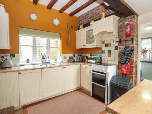 a kitchen with white cabinets and a brick wall at Sleepeezy in Kettlestone