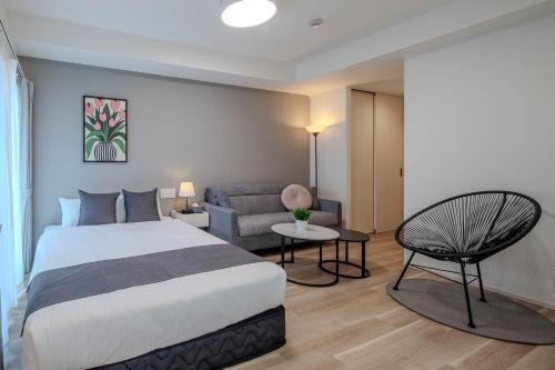 a bedroom with a bed and a chair and a couch at Socio Residential Hotel - ソシオ レジデンシャル ホテル in Hiroshima