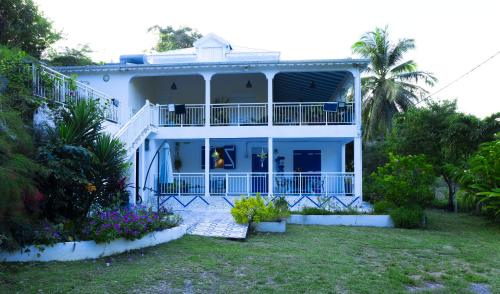 a white house with a balcony and a yard at VILLA EDEN Gosier in Le Gosier