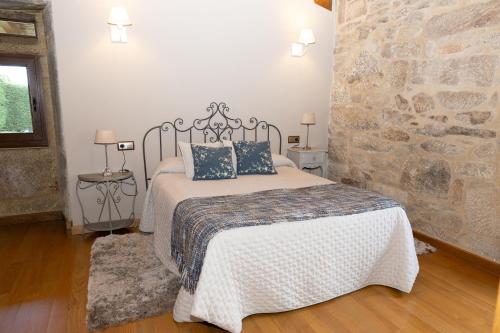 a bedroom with a bed and a stone wall at Casa San Son in Pontevedra