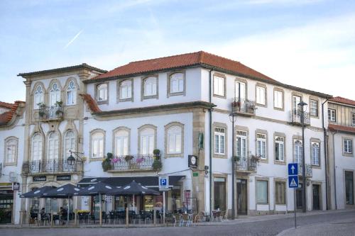 a large white building with tables and umbrellas at Raiano Guest House in Monção