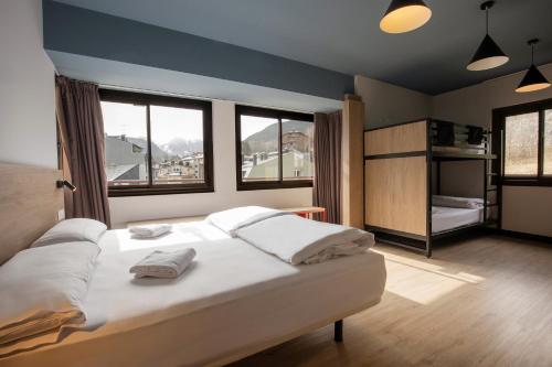 a bedroom with a large white bed with windows at Font Andorra Hostel by Nexta in La Massana