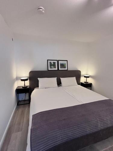a bedroom with a large white bed with two tables at Ostseeblick Apartment 2 in Scharbeutz