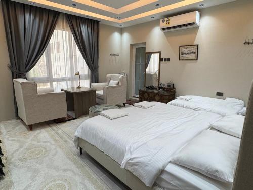 ALLATHBIAH Inn في Fulūj Sayghah: غرفة نوم بها سريران وكرسي ونافذة