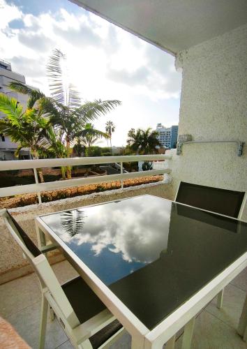 a table and chairs on a balcony with a reflection of the sky at Borinquen Vista Mar in Playa de las Americas