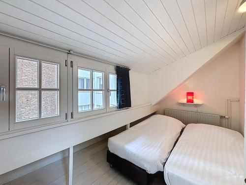 a bedroom with a bed and two windows at Maison No Catiau - De Panne in De Panne