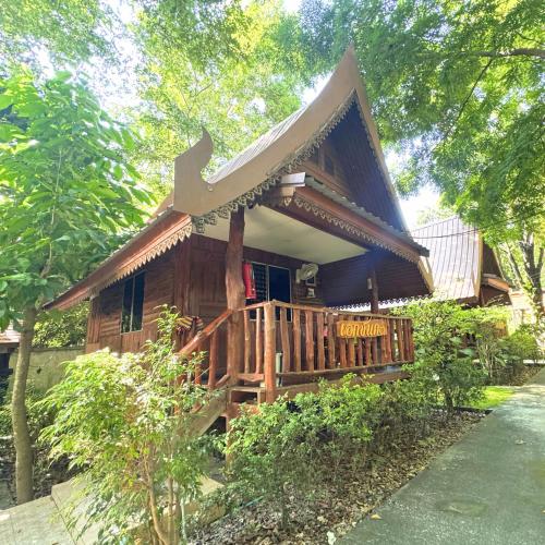 a wooden house with a porch and a balcony at Akchanok Homestay - Nature Retreat in Phitsanulok