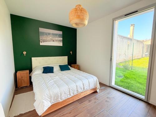 a bedroom with a bed and a green wall at Les Alizés, 3 étoiles in La Brée-les-Bains