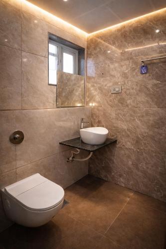 a bathroom with a toilet and a sink and a mirror at Hotel Navas Inn- Pure Veg, Kolhapur in Kolhapur