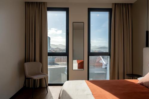 a bedroom with a bed and windows with a view at Essence Villas - Bath & Sunset in Ribeira Grande