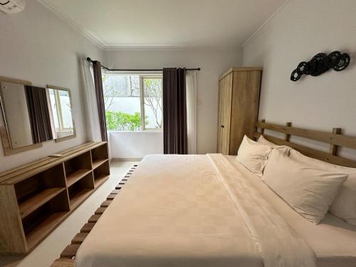 a bedroom with a large white bed with a window at Timber Sanctuary at Rancamaya in Ciawi Bogor