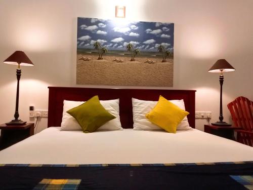 a bedroom with a bed with yellow and green pillows at Ceylonika Rest in Bentota