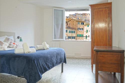 a bedroom with a bed with a blue blanket and a window at Gest Short Rent Siena 4 in Siena