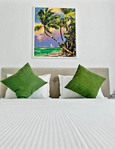 a bed with green pillows and a painting on the wall at Stefan Resort Mamaia Nord in Mamaia Sat/Năvodari