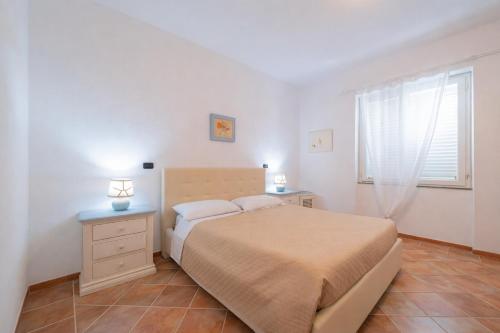a white bedroom with a bed and a window at Hotiday Villa Porto Rotondo in Porto Rotondo