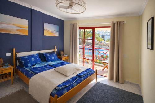 a bedroom with a bed with blue walls and a balcony at Sunny Playa del Cura in Playa del Cura
