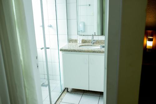 a white bathroom with a sink and a shower at Steel Valley Hotel in Ipatinga