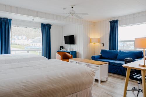 a hotel room with two beds and a blue couch at Riotel Perce in Perce
