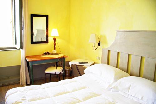 a bedroom with a bed and a desk with a mirror at Locanda Delle Mura Anna De Croy in Magliano in Toscana