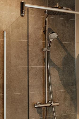 a shower with a glass door with a shower head at Hotel Tholen in Tholen