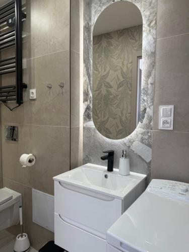 a bathroom with a white sink and a mirror at Odpocznij w Centrum in Wałbrzych