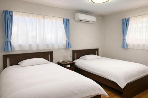 two beds in a room with blue curtains at 竹の宿b湖まで徒歩4分の好立地最大7人宿泊可能 in Fujikawaguchiko