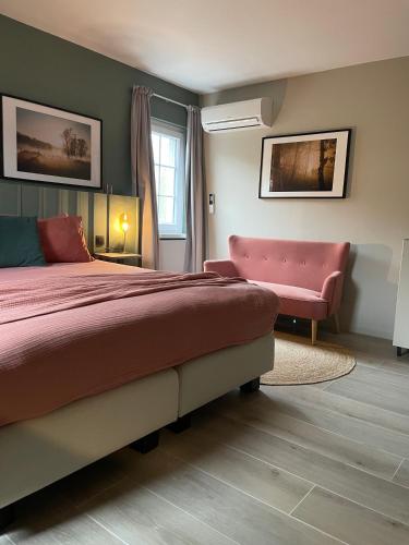 a bedroom with a large bed and a pink chair at B&B Maris Logies in Hasselt