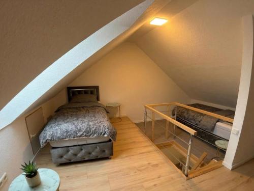 a attic bedroom with a bed and a staircase at Grenz-Apartment an der Aach in Rielasingen-Worblingen