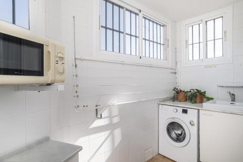 a white kitchen with a washing machine and a sink at Balconera 104 in Novo Sancti Petri