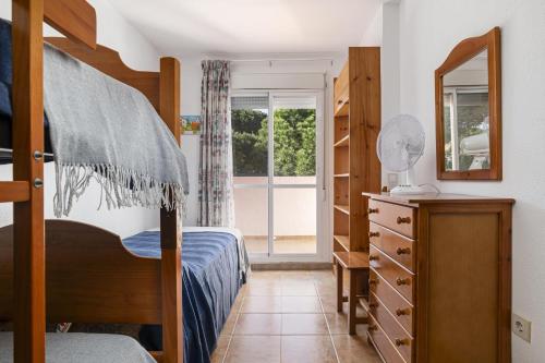 a bedroom with a bed and a dresser and a mirror at Balconera 104 in Novo Sancti Petri
