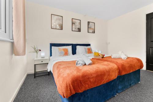 a bedroom with two beds with orange sheets at Centrally Located Apt with Parking in Walsall