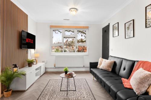 a living room with a black couch and a tv at Centrally Located Apt with Parking in Walsall