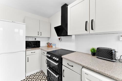 a kitchen with white cabinets and a black stove top oven at Centrally Located Apt with Parking in Walsall