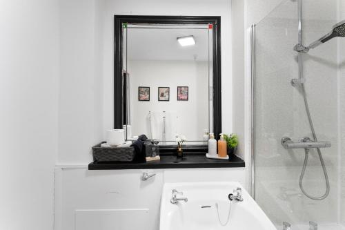 a bathroom with a mirror and a sink and a tub at Centrally Located Apt with Parking in Walsall